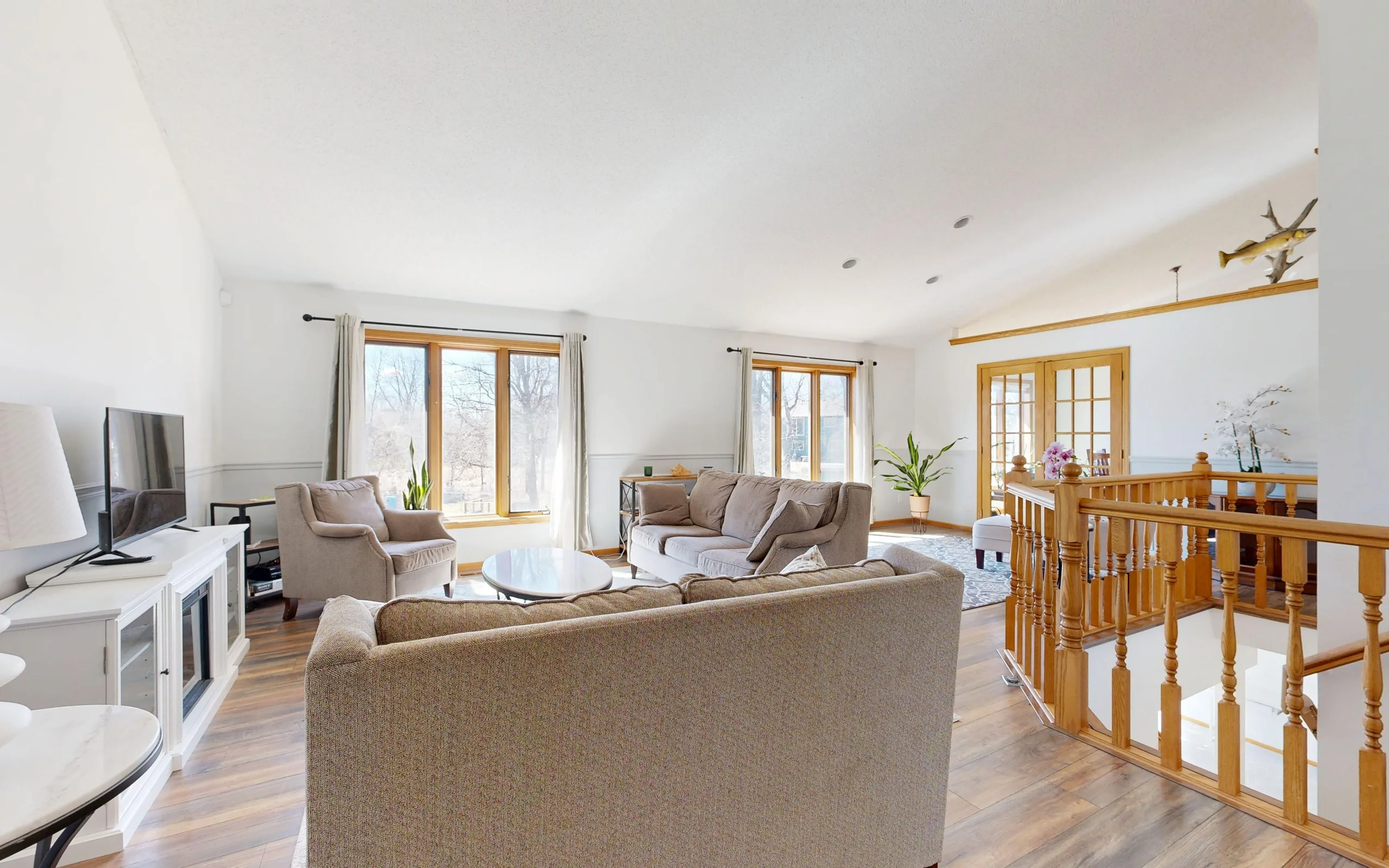 Salon lumineux d’un appartement, grandes fenêtres et mobilier clair